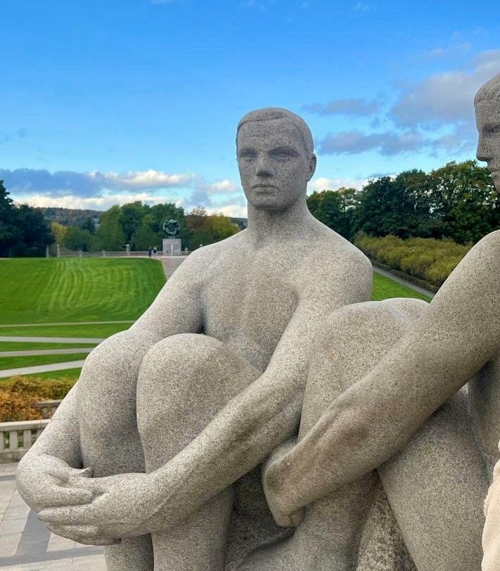 Steinskulptur eines sitzenden Mannes in einem Park